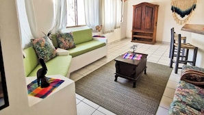 Uma sala de estar com um sofá verde, um armário de madeira e um ventilador de teto.