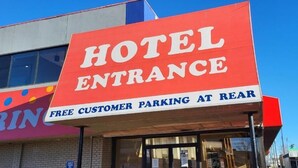 Ein Hotel Eingang mit Schild, das kostenlose Parkplätze für Gäste im Hinterhof anzeigt.