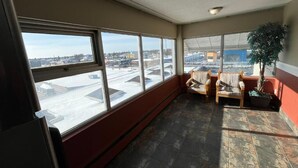 Ein großzügiger Balkon mit großen Fenstern, einem Sessel, einem kleinen Tisch und einem Blumentopf.