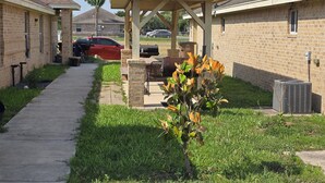 A residential area with brick houses, a covered patio, and a lawn. - Charming 2-bedroom apartment in Mercedes near the Outlets (Mercedes)
