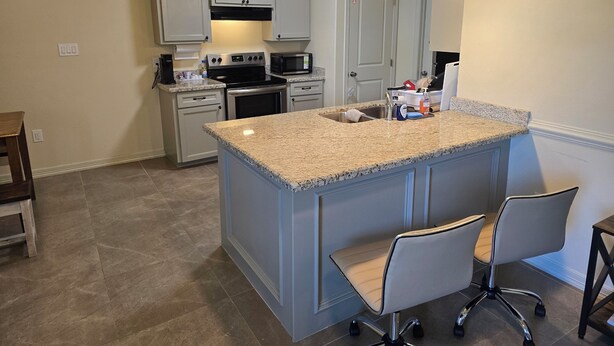 A kitchen with a granite countertop island, white cabinets, stainless steel appliances, and pendant lighting. - Charming 2-bedroom apartment in Mercedes near the Outlets (Mercedes)