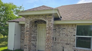 A single-story house with a brick facade, a front door, and a small porch. - Charming 2-bedroom apartment in Mercedes near the Outlets (Mercedes)