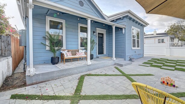 Ein blaues Haus mit Veranda, einer Bank und einem Blumentopf.