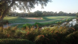 Un parcours de golf avec des obstacles d’eau, des bunkers de sable et un club-house en arrière-plan.
