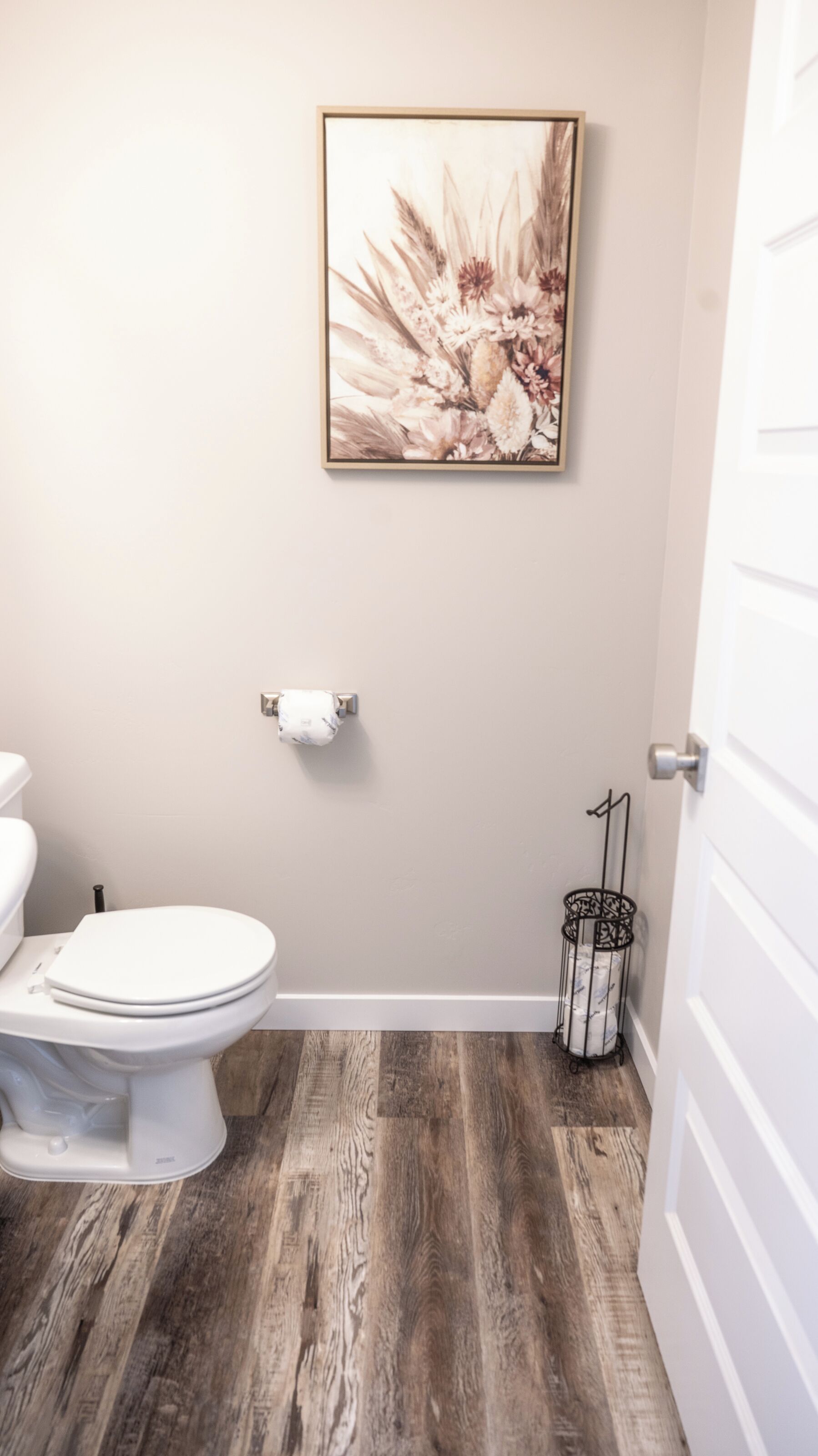 A bathroom with a toilet, a roll of toilet paper, and a trash can.