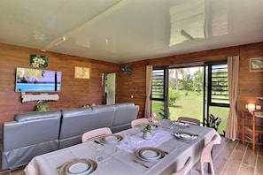 Enjoy meals in this stylish dining area with a large TV, comfortable seating, and a beautiful garden view.
