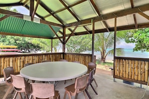 Relax in this beachside seating area with a table and chairs, offering a view of the ocean and surrounding vegetation.