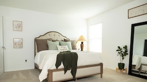 A bedroom with a bed, a bedside lamp, a potted plant, and a mirror. - Comfy Family Home w/ 4 rooms, WiFi, Office & Community Pool, in Rhome (Rhome)