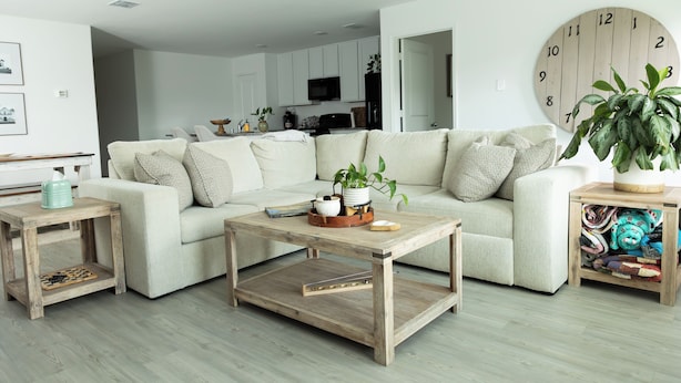 A living room with a sofa, coffee table, and side tables. There is a large clock on the wall and a plant on the side table. - Comfy Family Home w/ 4 rooms, WiFi, Office & Community Pool, in Rhome (Rhome)