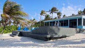 Un bâtiment situé au bord de la plage, doté d’une zone abritée et d’un escalier menant à la plage.