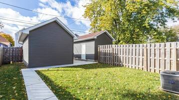A residential property with a covered garage, a wooden fence, and a grassy yard.