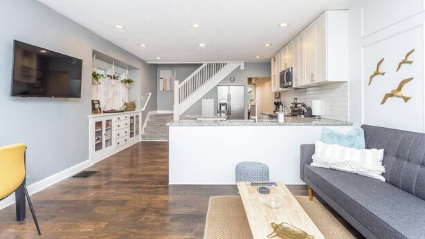A modern living room with a grey sofa, a wooden coffee table, and a TV mounted on the wall.