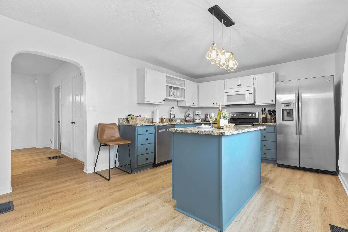 Una cocina moderna con una isla azul, electrodomésticos de acero inoxidable y muebles blancos.