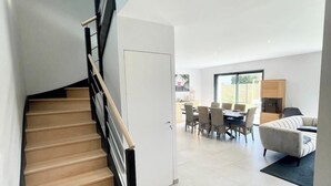 A modern interior with a staircase leading to a dining area. - Luxury Maison d'Architecte neuve de standing (Larmor-Baden)