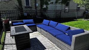 Un patio al aire libre con un sofá de mimbre y una mesa.
