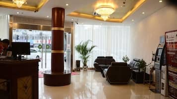 Um saguão de hotel com balcão de recepção, área de estar e um grande pilar.