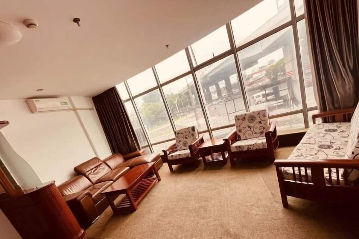 A room with large windows, a sofa, armchairs, and a patterned table.