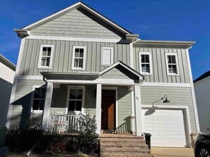 A two-story house with a front porch, a garage, and a well-maintained lawn.