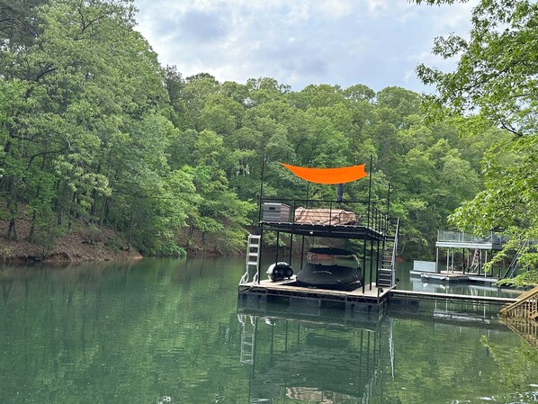 Un muelle flotante con zona de estar cubierta y un bote.