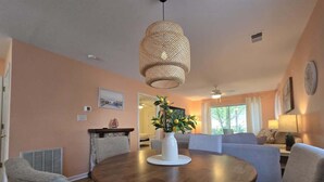 A dining area with a round table, chairs, a vase with flowers, and a hanging light fixture. - 1st Floor Plush Condo | W&D | Pool & Hot Tub (Myrtle Beach)