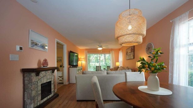 A living room with a fireplace, a dining table, and a large window. - 1st Floor Plush Condo | W&D | Pool & Hot Tub (Myrtle Beach)