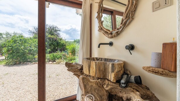 A bathroom with a large wooden basin, a mirror, and a shower area.