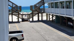 A beachside building with a wooden staircase leading to a balcony overlooking the beach. - BEACHFRONT w heated pool, steps to sand. Winter discounts Bath remodel 2 BR 1 BA (Gulf Shores)