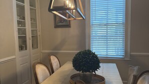A dining room with a long table, chairs, a hanging light fixture, a window with blinds, and a cabinet with glass doors. - Charming Century Old 3-bedroom house with WiFi and AC in fantastic Columbia (Columbia)