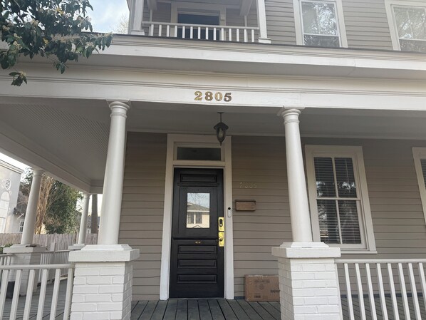 A two-story house with a porch, columns, and a black front door.