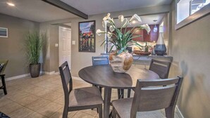 A dining area with a round table, four chairs, a potted plant, and a painting on the wall.