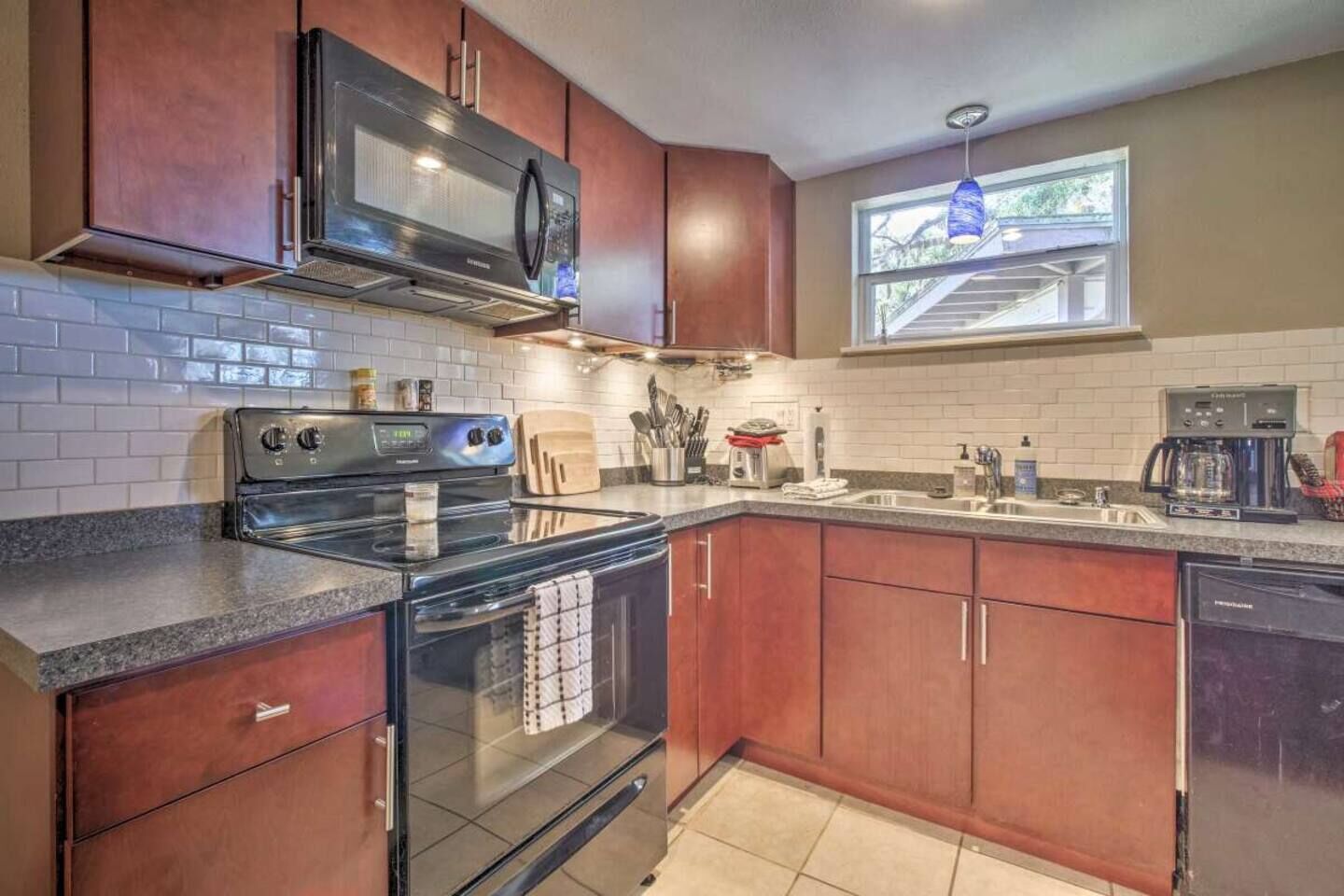 A modern kitchen with stainless steel appliances, wooden cabinets, and a window providing natural light.