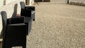 Een gebouw met een grindpad, zitplaatsen buiten en een grote boom.