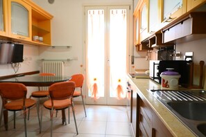 A kitchen with a dining table, chairs, a coffee machine, and a sink.