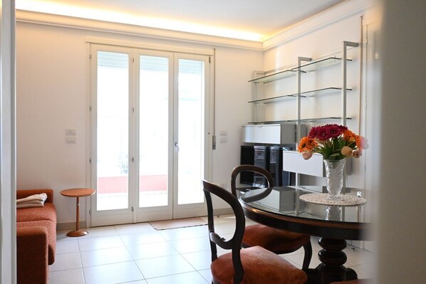 A dining area with a glass table, chairs, and a vase with flowers.