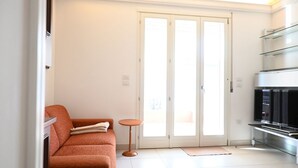 Un salon moderne comprenant un canapé, une petite table ronde, un téléviseur et une vitrine.