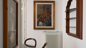 Une pièce avec un tableau encadré, un radiateur et une chaise en bois.