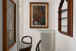 A room with a framed painting, a radiator, and a wooden chair.