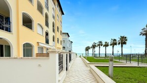 Un immeuble à plusieurs étages doté de balcons, d’un chemin bordé de carreaux et offrant une vue sur la mer.