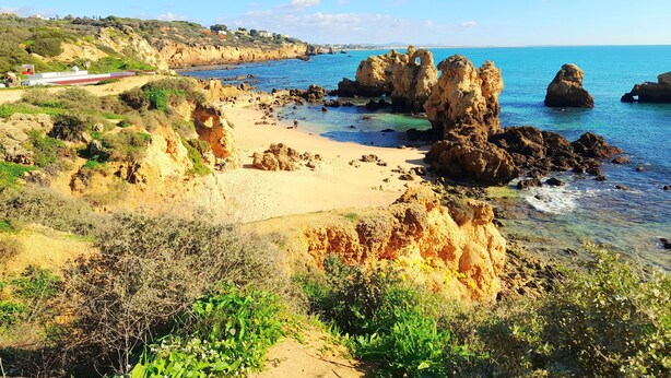 A coastal landscape with rocky formations, a sandy beach, and a clear blue sky. - Tropicana Holiday Apartments (Albufeira)