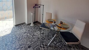 A room with a wooden ceiling, a TV mounted on the wall, a patterned floor, a table with chairs, and a window with blinds. - Tropicana Holiday Apartments (Albufeira)