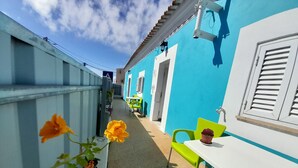 A narrow outdoor corridor with a blue wall, a white door, and a green chair. - Tropicana Holiday Apartments (Albufeira)