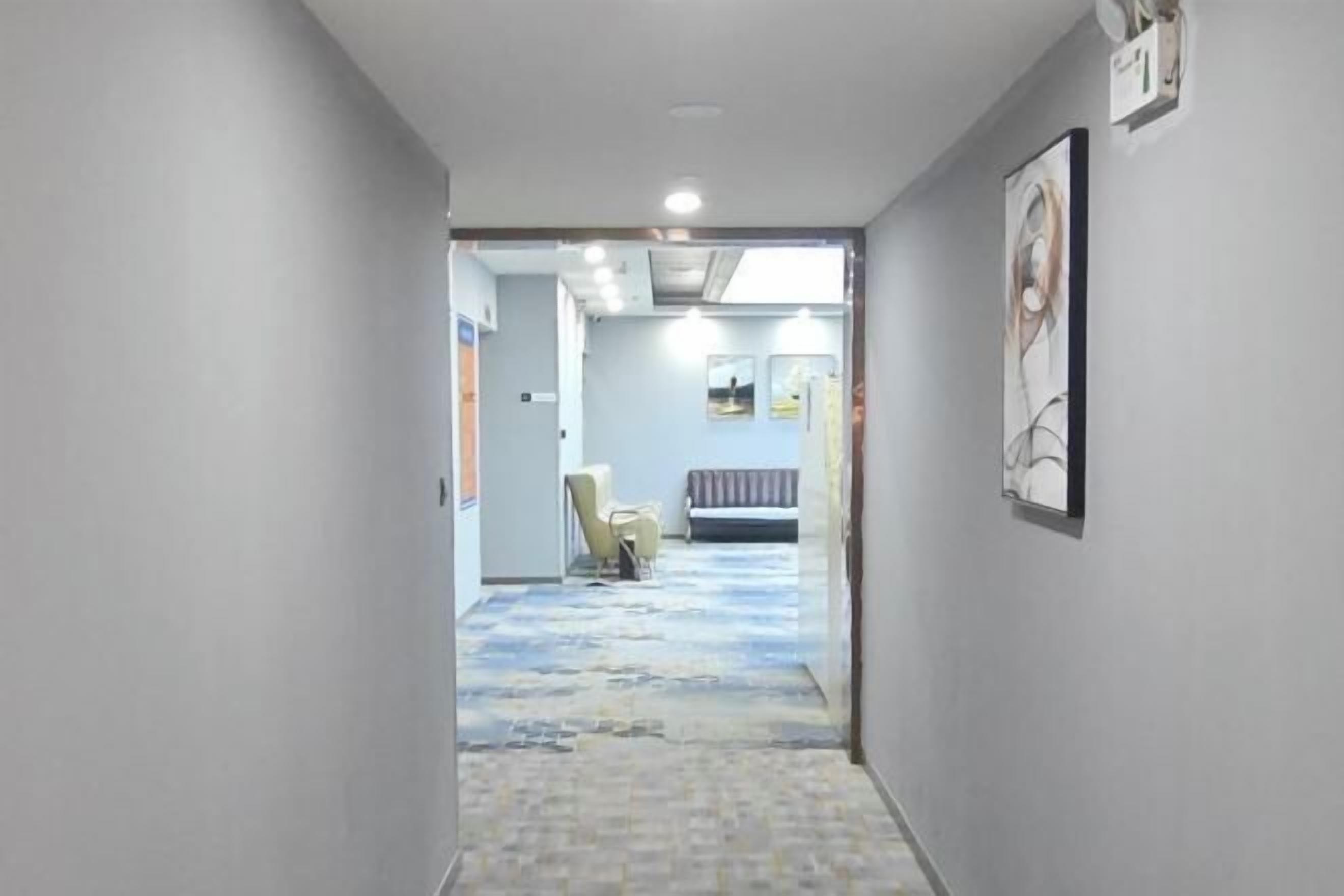 Ένας διάδρομος με ένα χαλί με σχέδια, ένα παγκάκι και μια καρέκλα.
