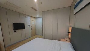 A hotel room with a large bed, a flat-screen TV mounted on the wall, a bedside table with a lamp, and a door leading to another room. - Yiju Hotel (Xi'an Bell and Drum Tower Ximen Children's Hospital Branch) (Xi'an)