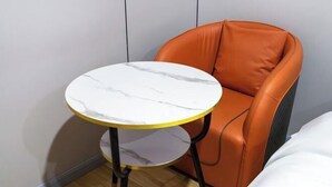 A small round table with a marble top, positioned next to an orange leather chair. - Yiju Hotel (Xi'an Bell and Drum Tower Ximen Children's Hospital Branch) (Xi'an)
