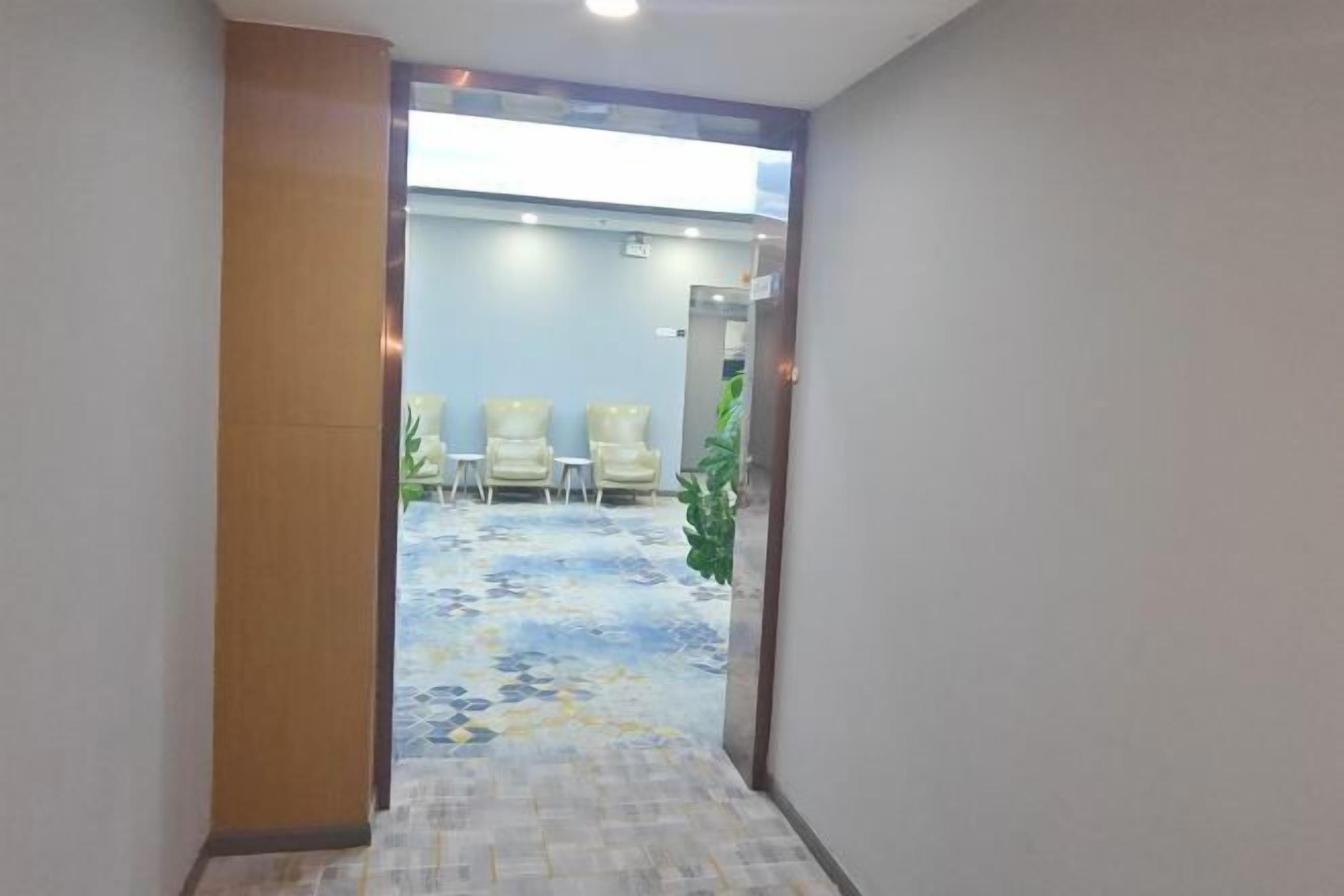 A hallway leading to a waiting area with chairs and a patterned floor.