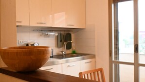 Een keuken met witte kastjes, een houten kom op het aanrecht en een raam met uitzicht.