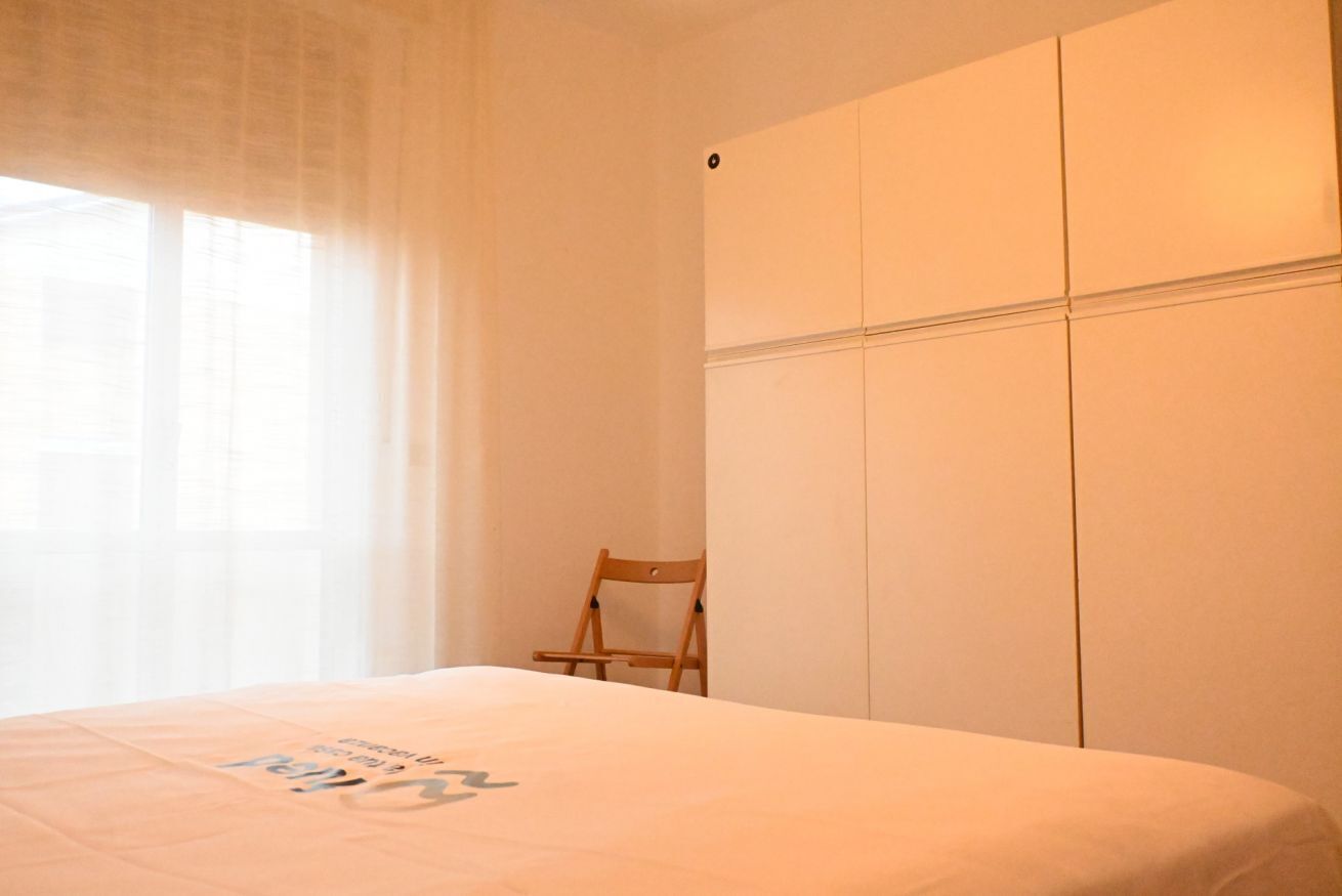 Une chambre à coucher avec un lit, une chaise en bois et une armoire.