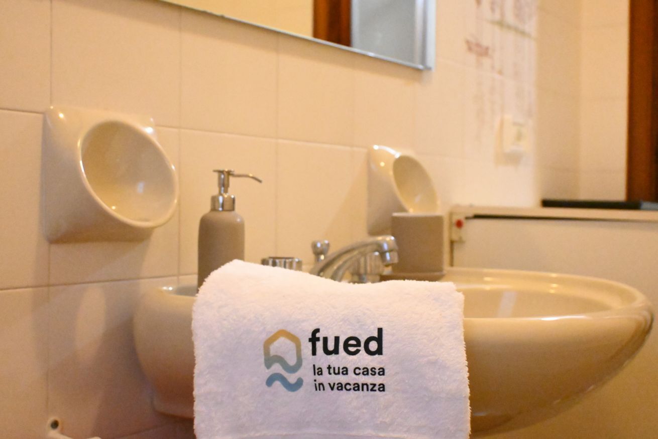 Une salle de bain équipée d’un lavabo, d’un distributeur de savon et d’une serviette ornée d’un logo.