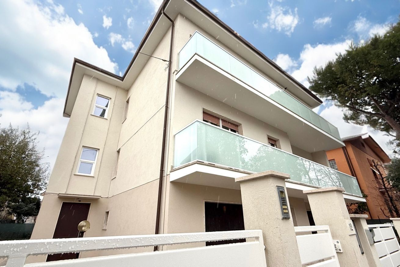 A multi-story residential building with a balcony, a door, and a window.