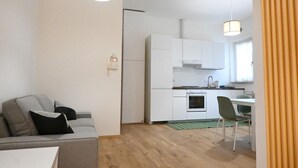 Ein kompakter Wohnbereich mit Küchenzeile, einer Couch, einer Essecke und einem Fenster.
